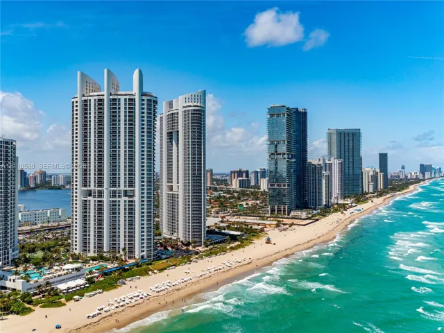 Coastal high-rise buildings situated along a sandy beach shoreline with direct ocean access