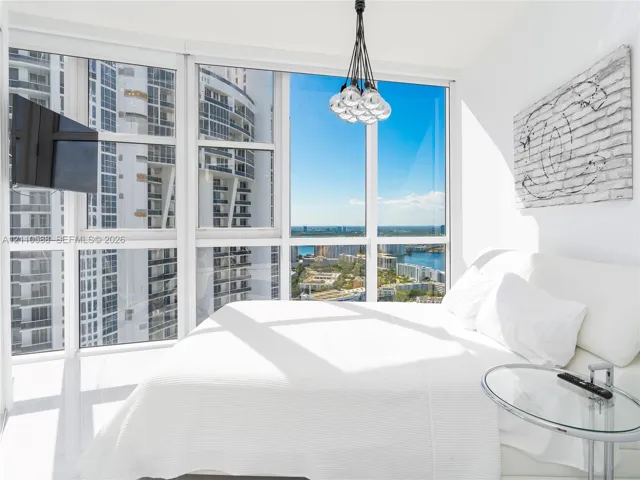 Floor-to-ceiling windows, polished flooring, and a multi-bulb hanging pendant light fixture