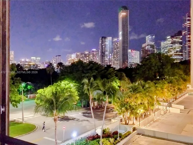 Panoramic cityscape featuring illuminated high-rise towers, mature palm trees, and landscaped grounds