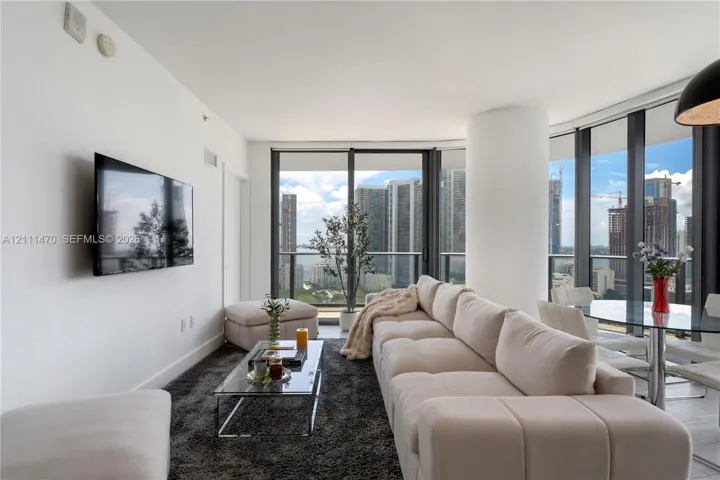 Floor-to-ceiling windows, high-rise urban skyline scenery, and neutral ceramic tile flooring