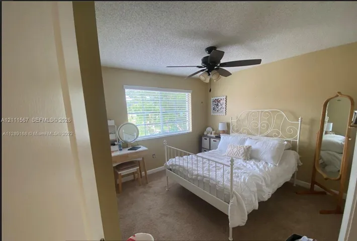 Bedroom featuring neutral wall paint, carpeted flooring, a ceiling-mounted light fixture with a fan, and a single-pane horizontal window