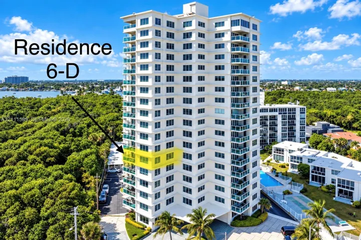 High-rise residential building featuring private balconies with glass railings, an exterior swimming pool, and dedicated paved parking