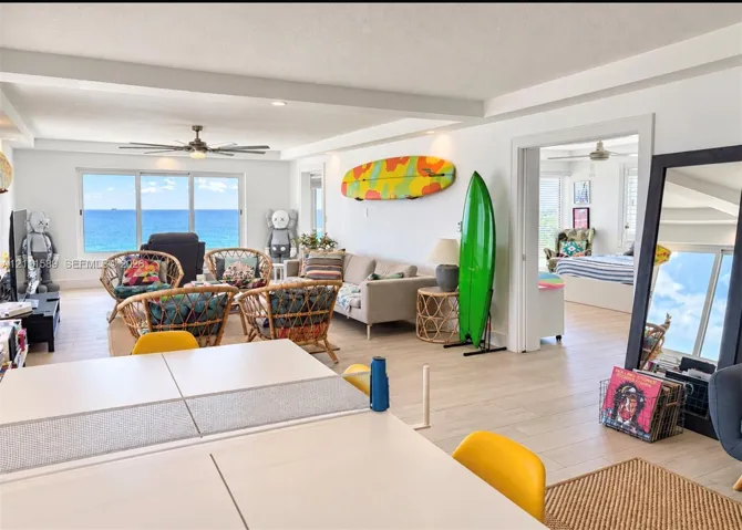 Open-concept interior featuring light-toned tile flooring, recessed ceiling lighting, a ceiling fan, and large picture windows highlighting coastal water
