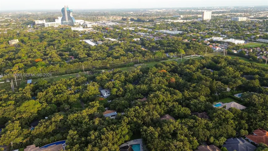 Aerial perspective of a heavily wooded residential landscape featuring mature canopy trees and expansive suburban greenery