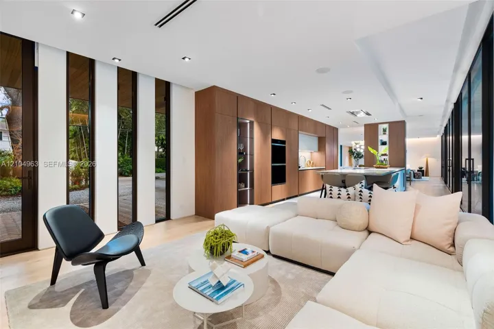 Open-concept space featuring wood-finish flooring, floor-to-ceiling windows, recessed lighting, and full-height wood cabinetry with built-in wall ovens