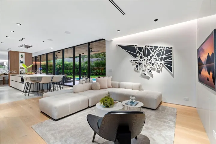 Open-concept floor plan featuring expansive floor-to-ceiling glass panel walls, wood-finish flooring, recessed lighting, and a modern kitchen island with integrated cabinetry