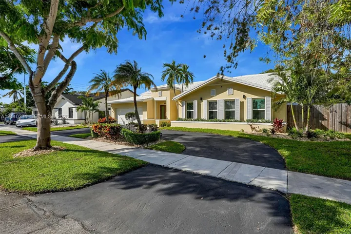 Exterior facade featuring a pitched tile roof, manicured landscaping with mature palm trees, and an expansive paved driveway