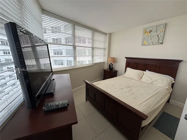 Floor-to-ceiling windows with horizontal blinds and large-format tile flooring