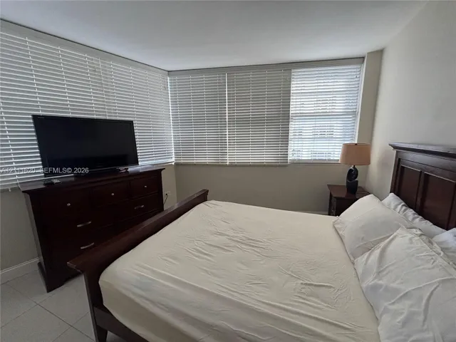 Large windows featuring horizontal blinds and neutral-tone tile flooring