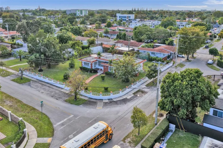 Corner lot property featuring a masonry perimeter wall, mature landscaping, and an expansive lawn