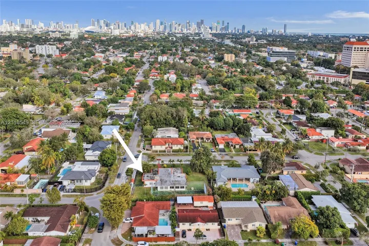 Aerial perspective of residential property featuring a flat-roof structure, expansive lot, and proximity to the urban skyline