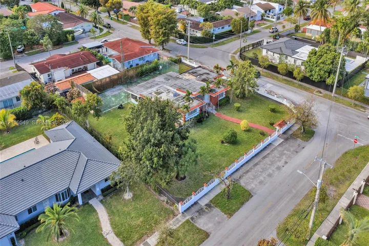 Corner lot residence featuring a fenced yard, private tennis court, mature trees, and a paved walkway