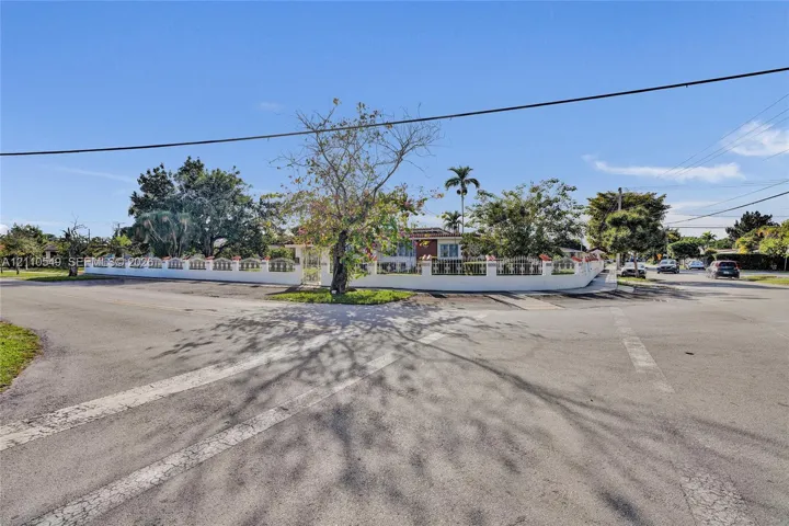 Corner lot property featuring a perimeter masonry wall with decorative accents, mature landscaping, and established trees