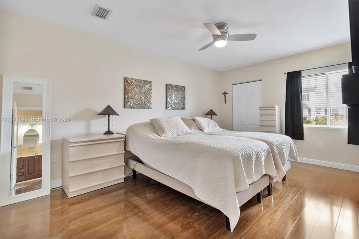 Room featuring wood-finish flooring, a ceiling fan with integrated lighting, and a dual-panel closet door