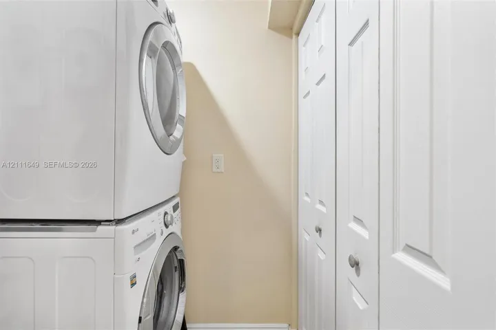 Stacked laundry unit with white finish and bifold closet doors