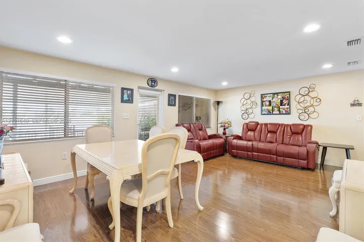 Open-concept interior featuring wood-finish flooring, recessed lighting, and expansive windows with horizontal blinds