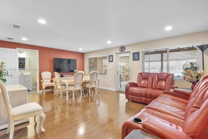 Open-concept interior featuring wood-finish flooring, recessed lighting, and a glass-paneled exterior door