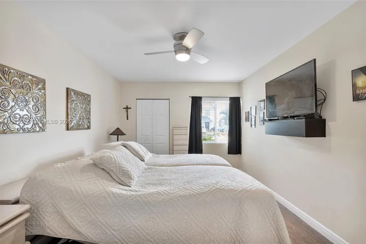 Bedroom featuring wood-finish flooring, a ceiling fan with integrated lighting, and a dual-panel closet door