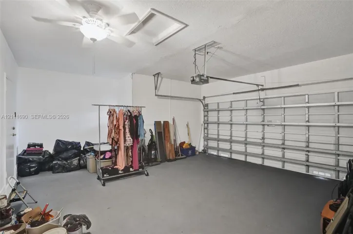 Garage interior featuring painted concrete flooring, an overhead automatic door opener, and a ceiling-mounted light fixture