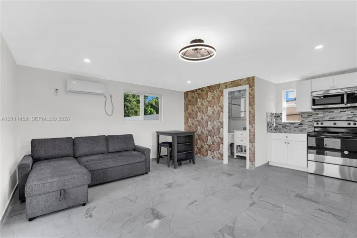 Interior featuring a built-in kitchen with white cabinetry and stainless steel appliances