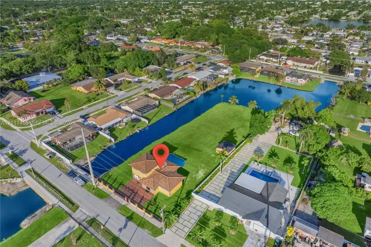 Aerial perspective of a single-family residence featuring a tiled roof, a private swimming pool, and direct canal frontage