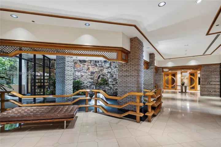 Interior featuring stone masonry pillars, tile flooring, recessed lighting, lattice woodwork accents, and a built-in water feature