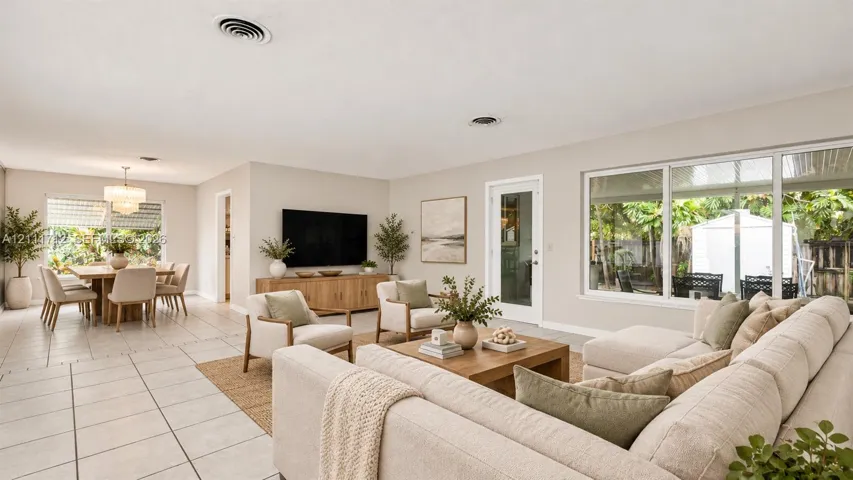 Virtually staged. Open-concept interior featuring large-format tile flooring, oversized windows, multi-pane glass door, and recessed lighting