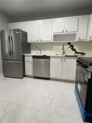 Kitchen featuring brand new stainless steel appliances, white shaker-style cabinetry, stone-finish countertops with matching backsplash, and hexagonal tile flooring.