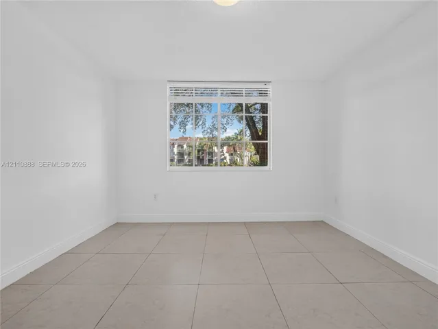 Neutral interior featuring large-format ceramic tile flooring, bright white walls, and a multi-pane window with integrated horizontal blinds