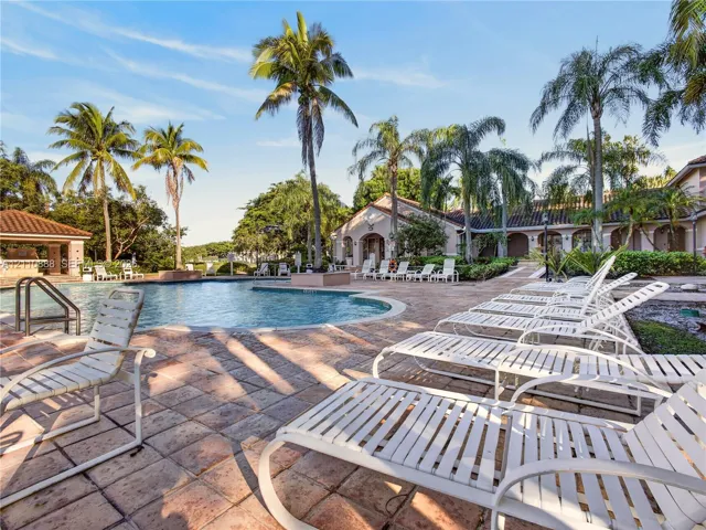 Swimming pool with metal handrails, stone paver decking, and a covered pavilion