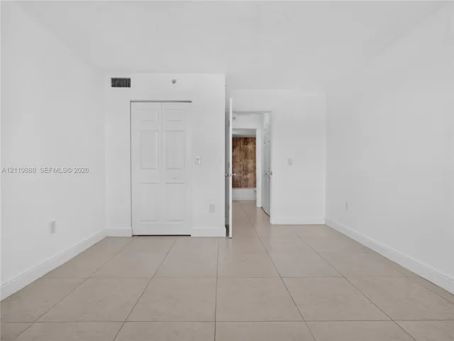 Neutral-toned ceramic tile flooring, white interior walls, and a white bi-fold closet door