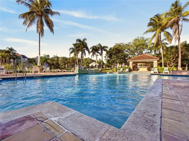 Outdoor swimming pool with tile decking, water feature, and a covered pavilion