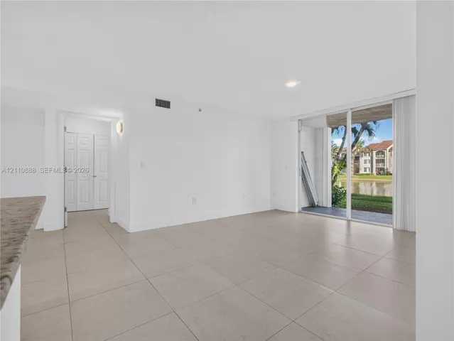Large-format ceramic tile flooring, sliding glass door, recessed lighting, and built-in closet with multi-panel doors