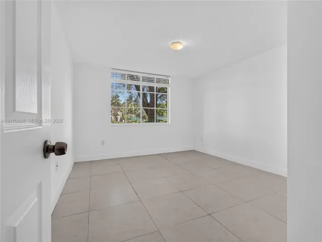 Neutral-toned tile flooring, multi-pane window with top transom, and flush-mount ceiling lighting