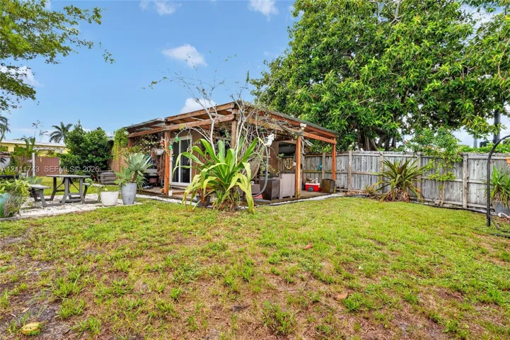 Rear exterior featuring a wood-frame pergola, concrete paver accents, and wood-panel privacy​​‌​​​​‌​​‌‌​‌‌​​​‌‌​‌​‌​‌​​​‌​​ fencing