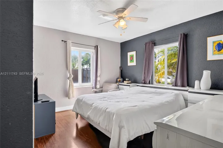 Wood-finish flooring, dual-tone painted walls, and ceiling-mounted light fixture with fan