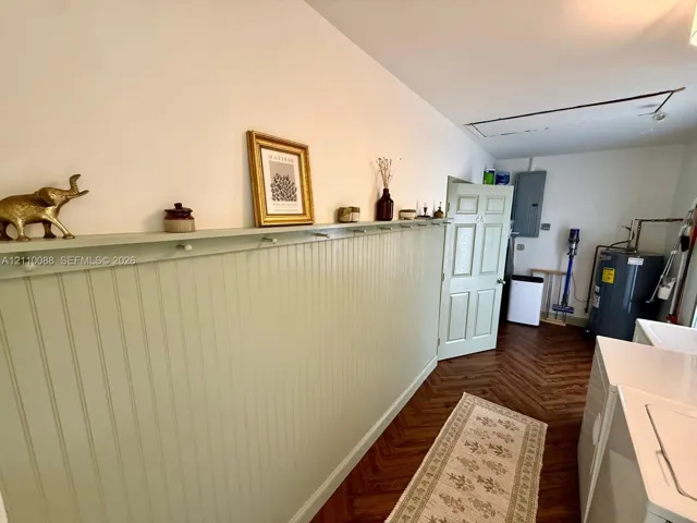 Herringbone-patterned wood-finish flooring, beadboard wall paneling, and an integrated wall-mounted shelf with pegs