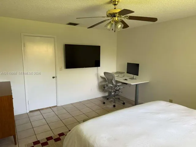Room featuring neutral walls, tile flooring, and a ceiling-mounted fan with integrated lighting
