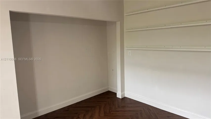 Recessed alcove featuring three tiers of built-in shelving and herringbone wood-finish flooring
