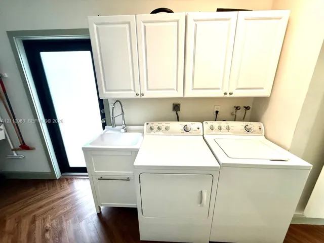 Utility space featuring white shaker-style wall cabinets, a built-in utility sink with a gooseneck faucet, and wood-finish flooring in a herringbone pattern