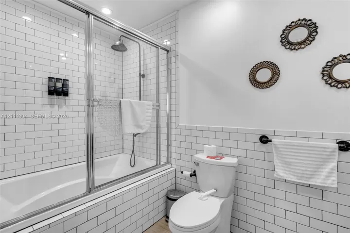 Subway tile wall treatments, chrome-framed glass shower enclosure, deep soaking tub, and wall-mounted metal towel rack