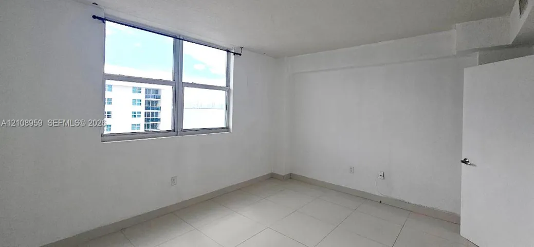 Room featuring white walls, large window with a horizontal pane, and neutral-tone tile flooring