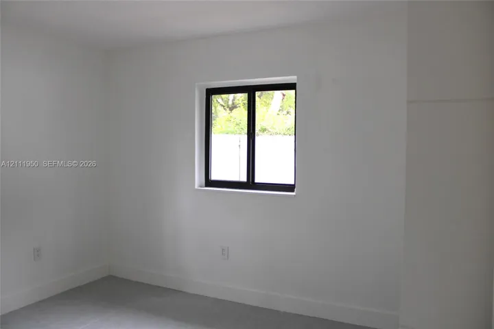 Neutral interior space featuring white walls, cool-toned tile flooring, and a single-hung window with a black frame