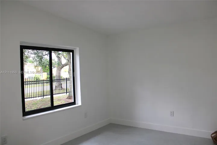 Interior space featuring neutral wall paint, smooth-finish flooring, and a sliding glass window with a black frame
