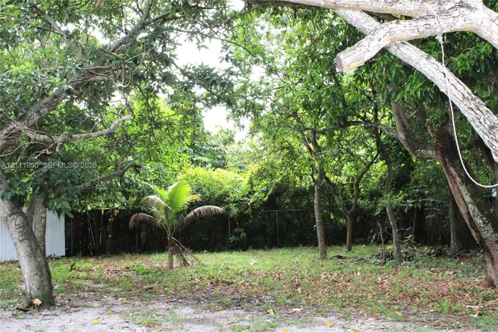 Expansive outdoor area featuring mature trees, established landscaping, and a perimeter fence