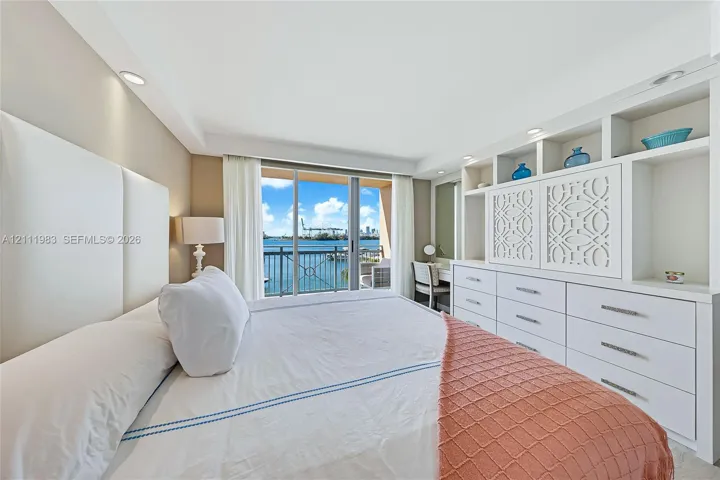 Built-in wall-to-wall cabinetry with integrated open shelving and drawers, floor-to-ceiling glass sliding doors, recessed lighting, and water scenery