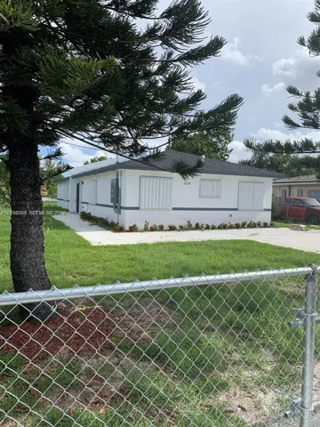 Single-story residence featuring a smooth stucco exterior, a hipped roof, metal hurricane shutters, and a concrete driveway