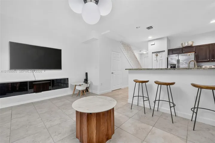 Open floor plan featuring tile flooring, stone-topped breakfast bar, built-in media console, and multi-bulb semi-flush mount lighting