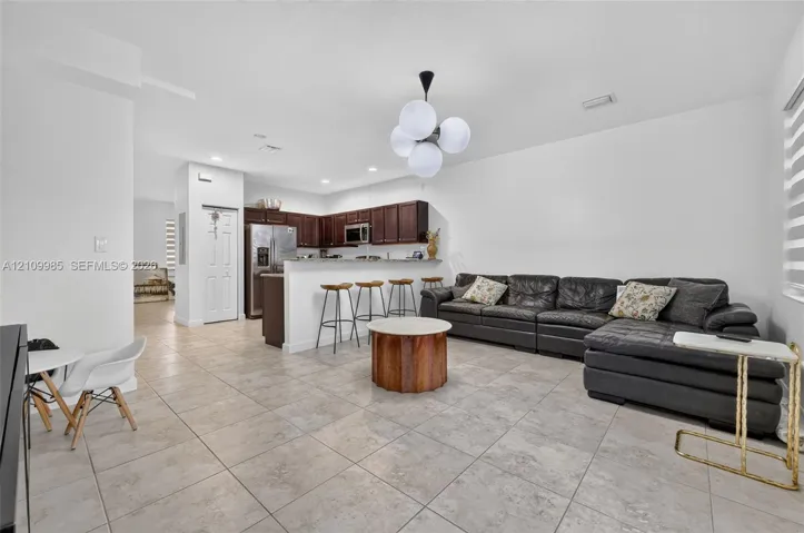 Kitchen featuring dark wood cabinetry, stainless steel appliances, and a breakfast bar, illuminated by a multi-globe pendant light fixture over tile flooring