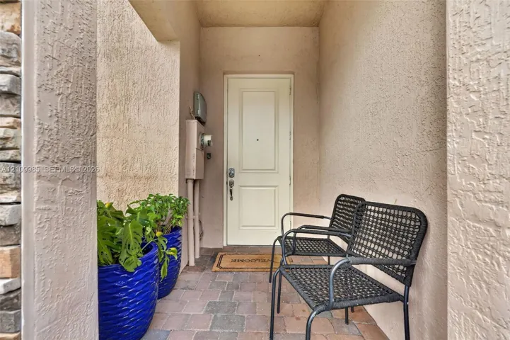 Covered entryway featuring a textured stucco facade, stone masonry accent, and paver flooring
